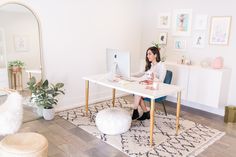 a woman sitting at a desk in front of a computer on top of a rug