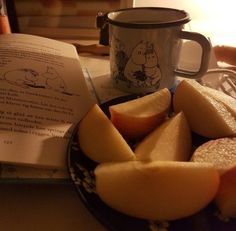 an open book and some sliced apples on a plate