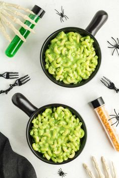 two black bowls filled with macaroni and cheese on top of a white table