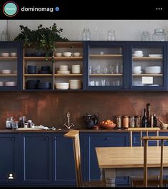 an image of a kitchen setting with blue cabinets and wooden table in the center area