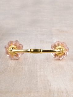 a pair of pink glass knobs on a wooden surface with a gold colored handle