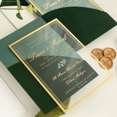 two green and gold wedding cards on top of each other next to some money coins