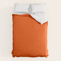 an orange and white bed with two pillows on top of it, next to a pillow case