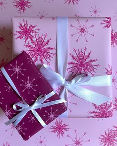 two presents wrapped in pink and white paper with snowflakes on them