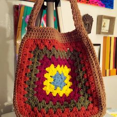 a crocheted bag hanging from a hook in a room with pictures on the wall