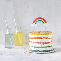 a rainbow cake with sprinkles and a bottle of lemonade in the background