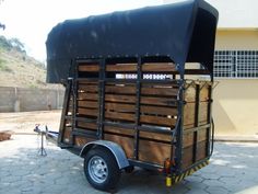 the trailer is loaded with wood and has a black tarp on it's back