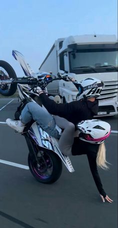 a woman is riding on the back of a motorbike in a parking lot