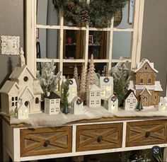 a christmas display in front of a window with small houses and trees on top of it