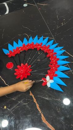 a person is holding an umbrella made out of paper flowers and plastic spikes on the floor