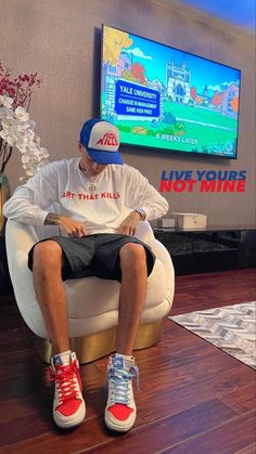 a man sitting in a chair with his feet up and wearing sneakers on the floor