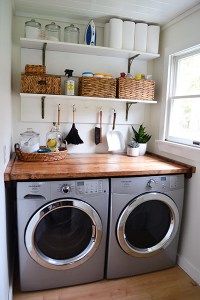 a washer and dryer in a small room with open shelving on the wall