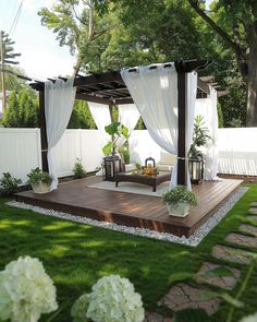 a wooden deck surrounded by white curtains and flowers