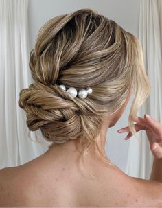 a woman with blonde hair and three pearls in her hair is shown from the back