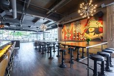 an empty restaurant with tables and stools in front of a painting on the wall