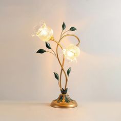 a lamp that is on top of a table with flowers in the middle and leaves growing out of it