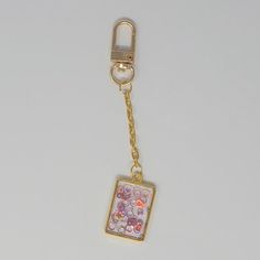 This minimalist and stylish purse charm is the perfect addition to your everyday carry planner! Featuring a chic design of floating shimmering circles in shades of red and pink in a gold rectangular bezel pendant, that hangs from a gold chain with a gold clasp. Perfect for any occasion or as a gift to a loved one, this planner/purse charm is sure to be a treasured favorite. Gold Bag Charm With Charms For Everyday Use, Trendy Rectangular Bag Charm Gift, Trendy Rectangular Keychains For Gifts, Trendy Gold Keychain For Everyday Use, Gold Jewelry With Removable Charms For Everyday, Elegant Gold Bag Charm For Gift, Elegant Gold Bag Charm As Gift, Gold Rectangular Bag Charm For Gift, Rectangular Gold Bag Charm For Gift