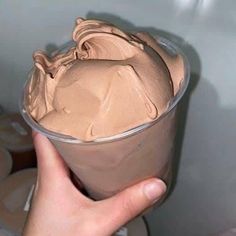 a hand holding a cup with chocolate frosting in it