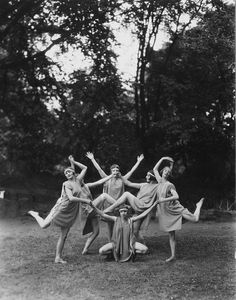 an old black and white photo of five women in dresses posing for the camera with their arms around each other