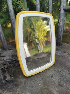 a small yellow and white television sitting on top of a wooden table next to trees