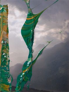 two kites flying in the sky with mountains in the back ground and clouds in the background