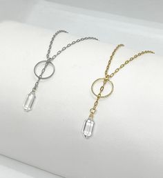 Handmade Dainty Geometric Hammered Circle and Rock Crystal Point Lariat Y Necklace. Choice of Gold Plated (18k gold) or Silver Tone. Adjustable 15.5"-17.5" (not including 1 3/4" drop) with lobster clasp closure. The layered lariat pendant design features a slender chain drop with a 1/2" tall Rock Crystal cut into a point shape and a lightly hammered circle (5/8"). Wire wrapping and hammering are done by hand. Comes in a gift bag.  DETAILS: Measurements (approximate): Chain is 17.5" long (15.5" plus 2" extender). Drop is 1.75. Chain is 1.7mm wide. Circle is 5/8" in diameter and 1mm in thickness. Crystal is 1/2" tall.  Materials: Genuine Rock Crystal Gold Plated: 18k gold plated stainless steel chain. Real gold plated brass circle. Gold plated copper wrapping wire. Silver Tone: Silver tone s Bag Details, Y Necklace, Pendant Design, Rock Crystal, Crystal Points, Stainless Steel Chain, Real Gold, Gift Bag, Lobster Clasp