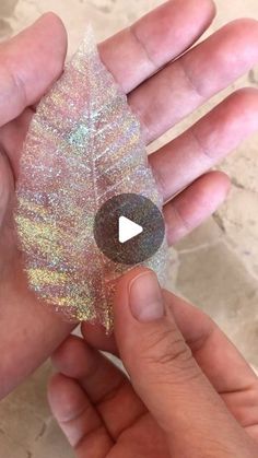 someone is holding a glittered leaf in their hand with a video playing on it