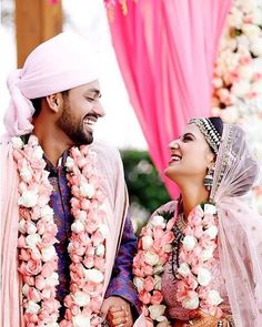 a man and woman standing next to each other in front of a flower covered archway