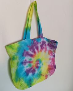 a tie - dyed bag hanging on the wall with it's handles down,