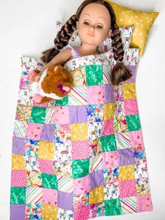 a doll laying in a bed with a blanket