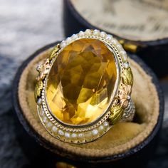 This antique ring features of both the Art Deco and Retro 1940s period. The central oval cut citrine is accented by an engraved border and two sections of seed pearls carefully set onto a wire. The shoulders of the ring are accented with openwork and two-tone floral designs. The ring is crafted in 14k white gold with yellow and rose gold accents, and is currently a size 6. Please note that one seed pearl seems to be missing, but it does not detract from the beauty or symmetric look of the ring. Rose Gold Accents, Antique Ring, Citrine Ring, Seed Pearl, Antique Rings, Pearl Ring, Floral Designs, Tri Color, Gold Accents