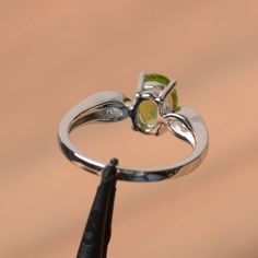 It is a natural peridot ring. The main stone is 6 mm*8 mm oval cut.weight about 1.33 carats. The basic metal is sterling silver and plated with rhodium. To change the metal to a solid gold (white/rose) or platinum is also available, please ask for a quotation if you want. You can also go to my shop Home for more elegant rings: https://www.etsy.com/shop/godjewelry?ref=hdr_shop_menu Peridot is the August birthstone More peridot rings: https://www.etsy.com/shop/godjewelry?section_id=20709252 Custom Silver Peridot Ring With Birthstone, Silver Peridot Gemstone Ring, Classic Green Peridot Ring, Peridot Gemstones For Anniversary, May Birthstone, Silver Peridot Rings With Polished Finish, Birthstone, Green Gems, Peridot Ring, Elegant Ring