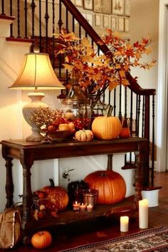 pumpkins and gourds are arranged on a table in front of the stairs