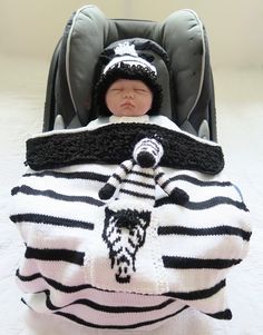 a baby sleeping in a car seat wearing a zebra blanket and knitted animal hat