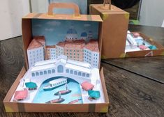 an open cardboard box with paper cut out of it and some buildings in the background