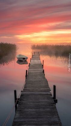 a small boat is docked at the end of a pier as the sun goes down