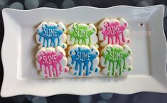 four decorated cookies on a white plate with the words slime, slime, slime and slime