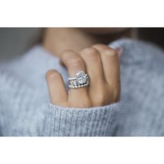 a woman's hand with a diamond ring on her finger, wearing a blue sweater