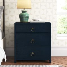 a night stand with a lamp on it next to a blue chest of drawers in a bedroom