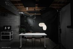 a table and chairs in a dark room with lights on the ceiling, lighting equipment set up around it