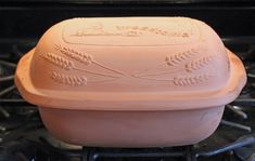 a pink casserole dish sitting on top of an oven