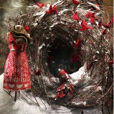 a woman standing next to a wreath with red flowers