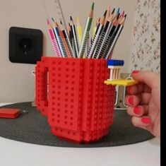 a cup made out of legos with pencils in it