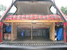 the back end of a red truck with luggage in it's cargo compartment and an open trunk