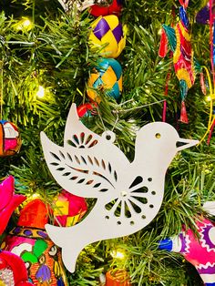 a white bird ornament hanging from a christmas tree with other ornaments around it