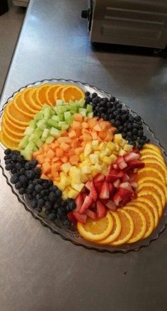 a platter filled with sliced fruit on top of a metal counter