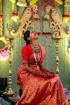 a woman sitting in front of a decorated stage with flowers on it's head