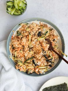 a bowl filled with rice and vegetables on top of a white table next to other dishes