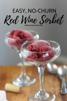 two glasses filled with red wine sorbet sitting on top of a wooden table