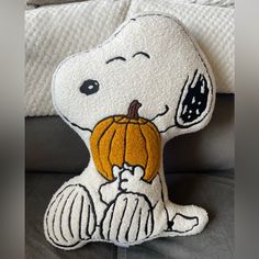 a snoopy stuffed animal with a pumpkin on it's chest sitting on a couch